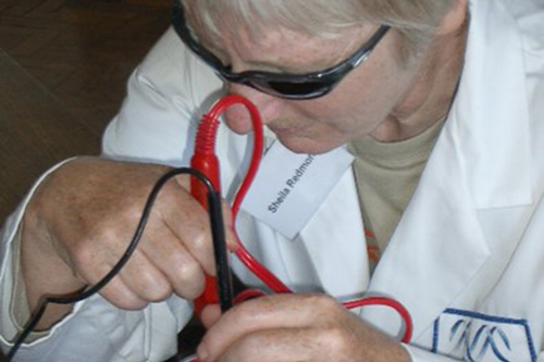 A visually impaired student in a white coat doing science